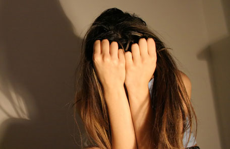 Imagem de uma menina escondendo o rosto com as mãos