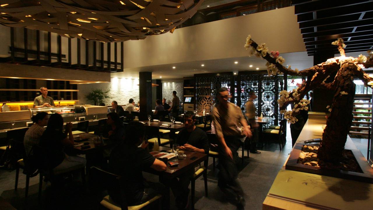 Imagem exibe ambiente escuro de restaurante japonês.