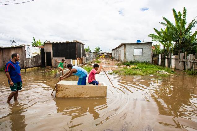 Crianças usam geladeira quebrada como barco para atravessar a rua no Jardim Pantanal