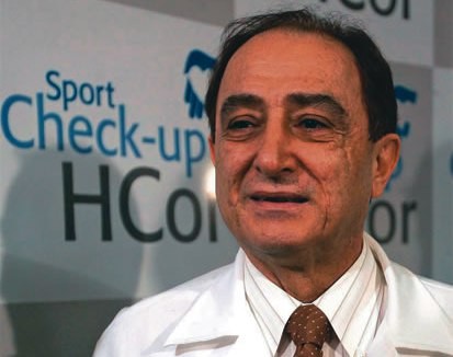Nabil Ghorayeb aparece em imagem sorrindo, vestindo jaleco branco e gravata escura