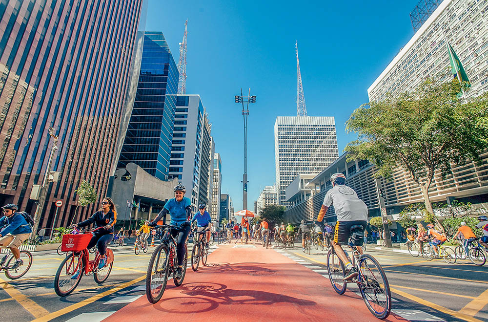 Ciclovia Paulista com ciclistas e prédios à vista.