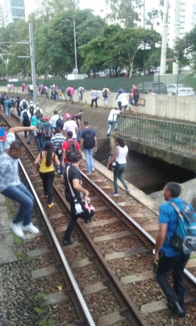 Pessoas andam nos trilhos do trem