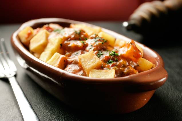 Porção de batatas-bravas com caldo de mariscos no molho de tomate Porção de batatas-bravas com caldo de mariscos no molho de tomate