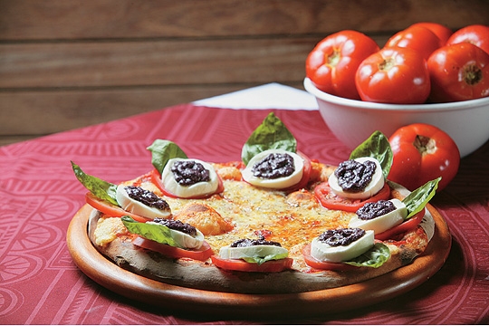 Caprese: cobertura de mussarela e fatias de tomate coroadas por uma composição de mussarela de búfala, folhas de manjericão gigante e pesto de azeitona preta