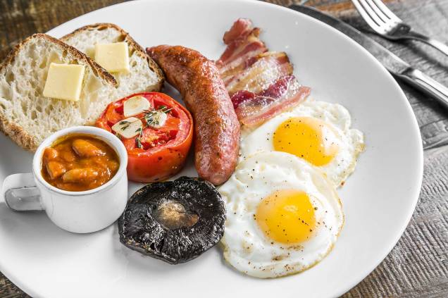 Café da manhã inglês: linguiças, bacon, cogumelo, tomate assado, ovo, bacon, feijão e torradas
