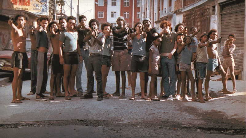 Foto mostra vários jovens juntos apontando armas para frente, no filme "Cidade de Deus"