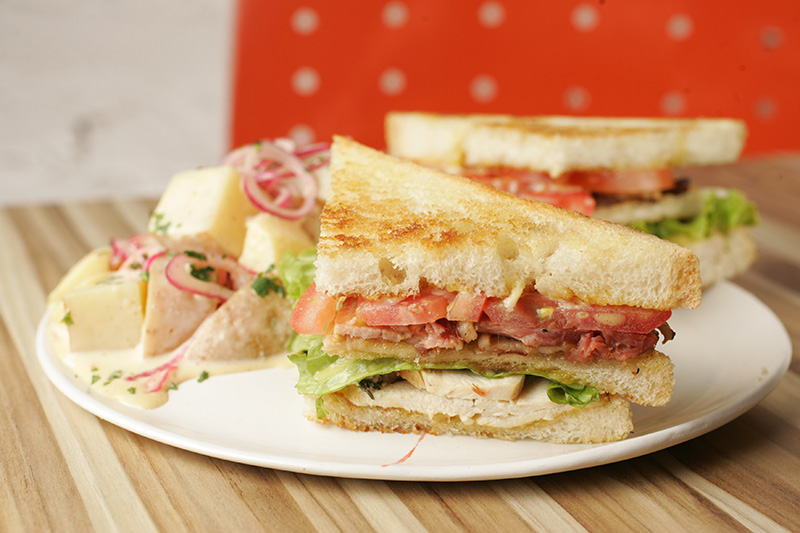 Club sandwich com peito de frango e bacon com salada e batata