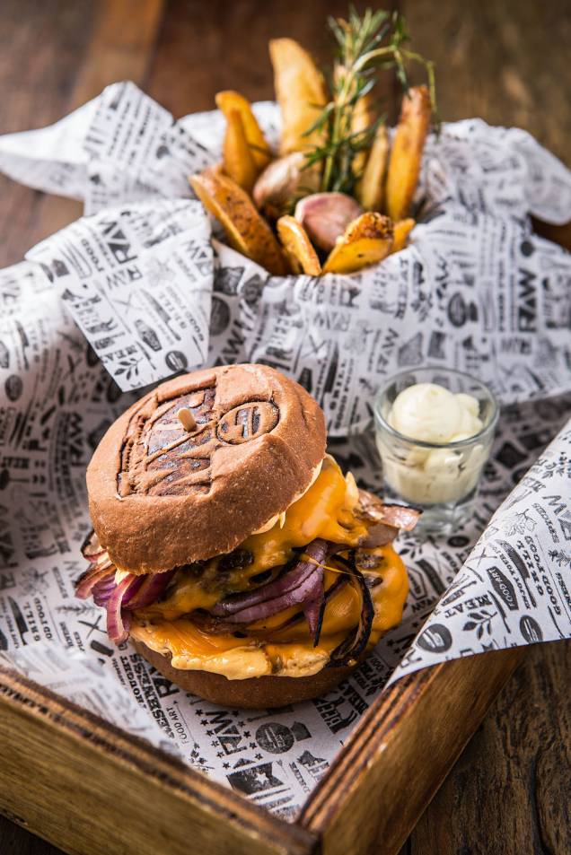 Dois discos de carne, queijo cheddar e cebola-roxa no pão australiano