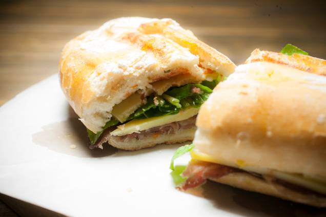 No pão semi-italiano, o sanduíche de copa curada, queijo campo redondo, rúcula e molho de tomate