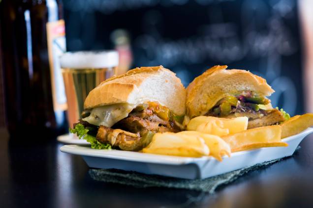O sanduba de pernil de estádio vem todo ajeitado no prato junto de fritas O sanduba de pernil de estádio vem todo ajeitado no prato junto de fritas
