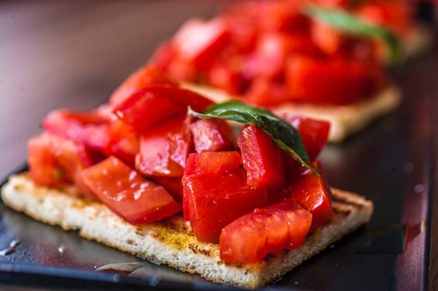 O trio de bruschettas com pedaços de tomate, folhas de manjericão e azeite O trio de bruschettas com pedaços de tomate, folhas de manjericão e azeite