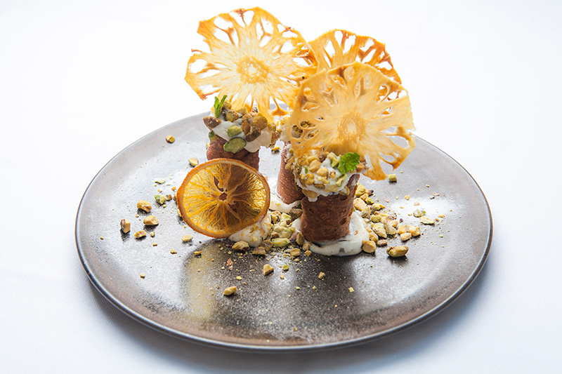 Uma das sobremesas traz um trio de cannoli coberto por rodelas de abacaxis