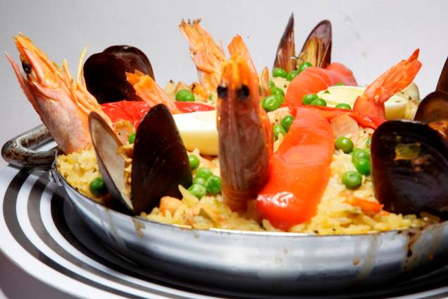 Paella valenciana : elaborada com arroz , açafrão, frango, legumes, bacon e frutos do mar