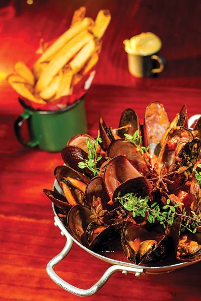 Moules frites à l´indienne: mariscos cozidos no molho de tomate ao curry amarelo, cardamomo e anis