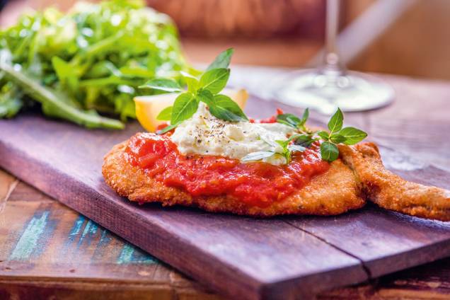 Costeleta suína à parmigiana: na companhia de salada Costeleta suína à parmigiana: na companhia de salada