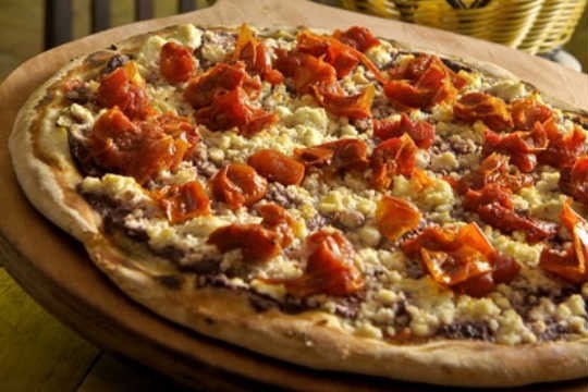 A pizza Mediterrâneo é feita com finas fatias de berinjela, tomate seco picadinho e ricota regada ao pesto de azeitona preta