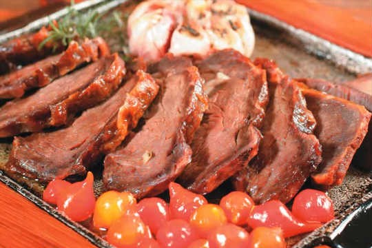 Uma das campeãs de pedidos do brasileiro Mocotó: carne de sol na chapa com alho assado, pimenta-biquinho e chips de mandioca