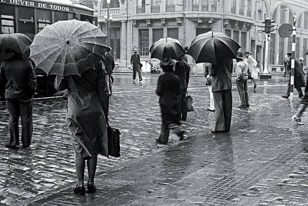 Pessoas se protegem da chuva na Avenida São João: a cidade na década de 40 Pessoas se protegem da chuva na Avenida São João: a cidade na década de 40