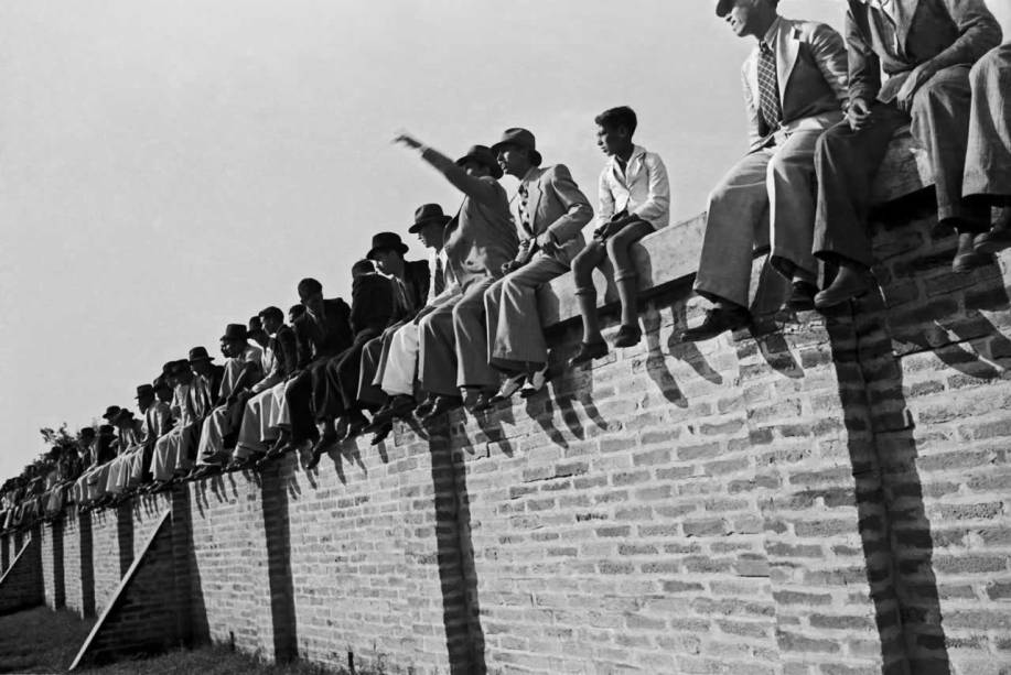 Torcedores assistem a jogo de futebol, em 1940: sombra, luz e grafismo
