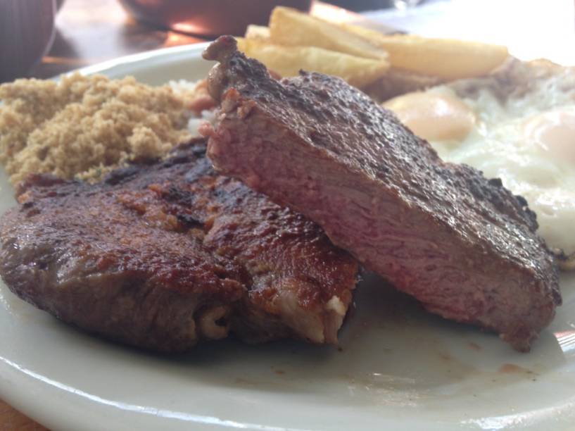 A opção de bife ancho à cavalo com acompanhamentos à vontade