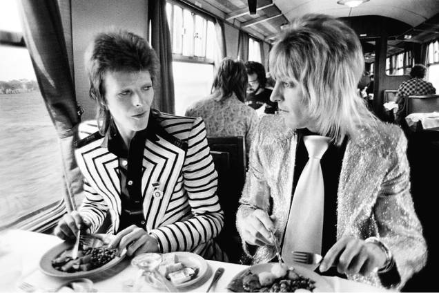 David Bowie e Mick Ronson almoçando em trem, em 1973