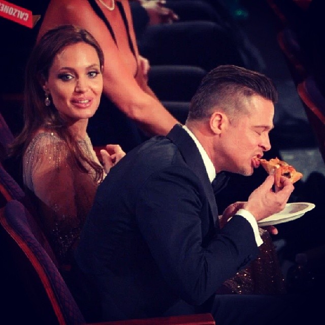 Brad Pitt traçando uma pizza ao lado de Angelina Jolie
