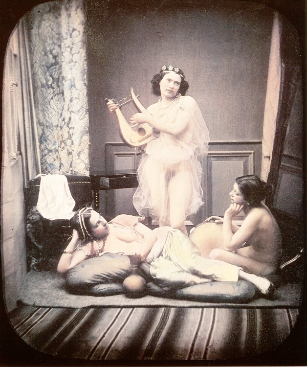Three almost nude women are shown in a studio setting with elements of a harem as well as ancient Greece. 1850. The woman in the center is holding a lyra and is wearing a transparent veil. Hand-colored stereoscopic-daguerreotype in a contemporary case.    (Photo by Galerie Bilderwelt/Getty  Images)