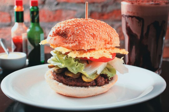 Hambúrguer artesanal: ladeado por picles, alface, tomate e disco de parmesão crocante