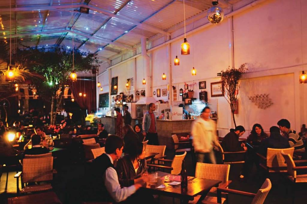 O descontraído ambiente: luminárias feitas com garrafões de vinho e, ao fundo, uma pitangueira