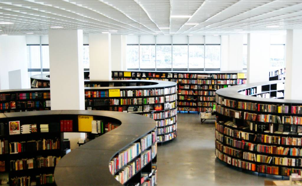 Imagem mostra estantes de livros dispostas em espaço