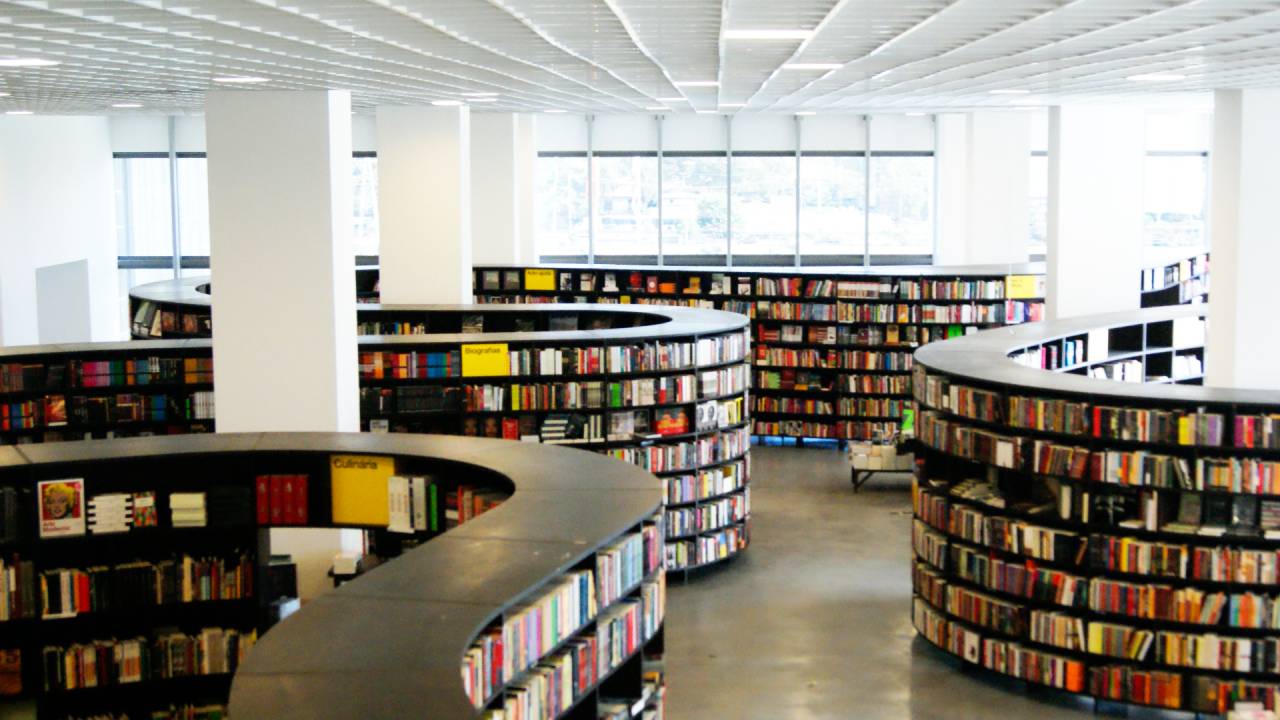 Imagem mostra estantes de livros dispostas em espaço