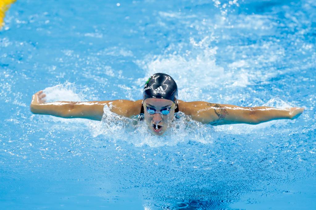 A foto mostra um atleta nadando em piscina durante competição