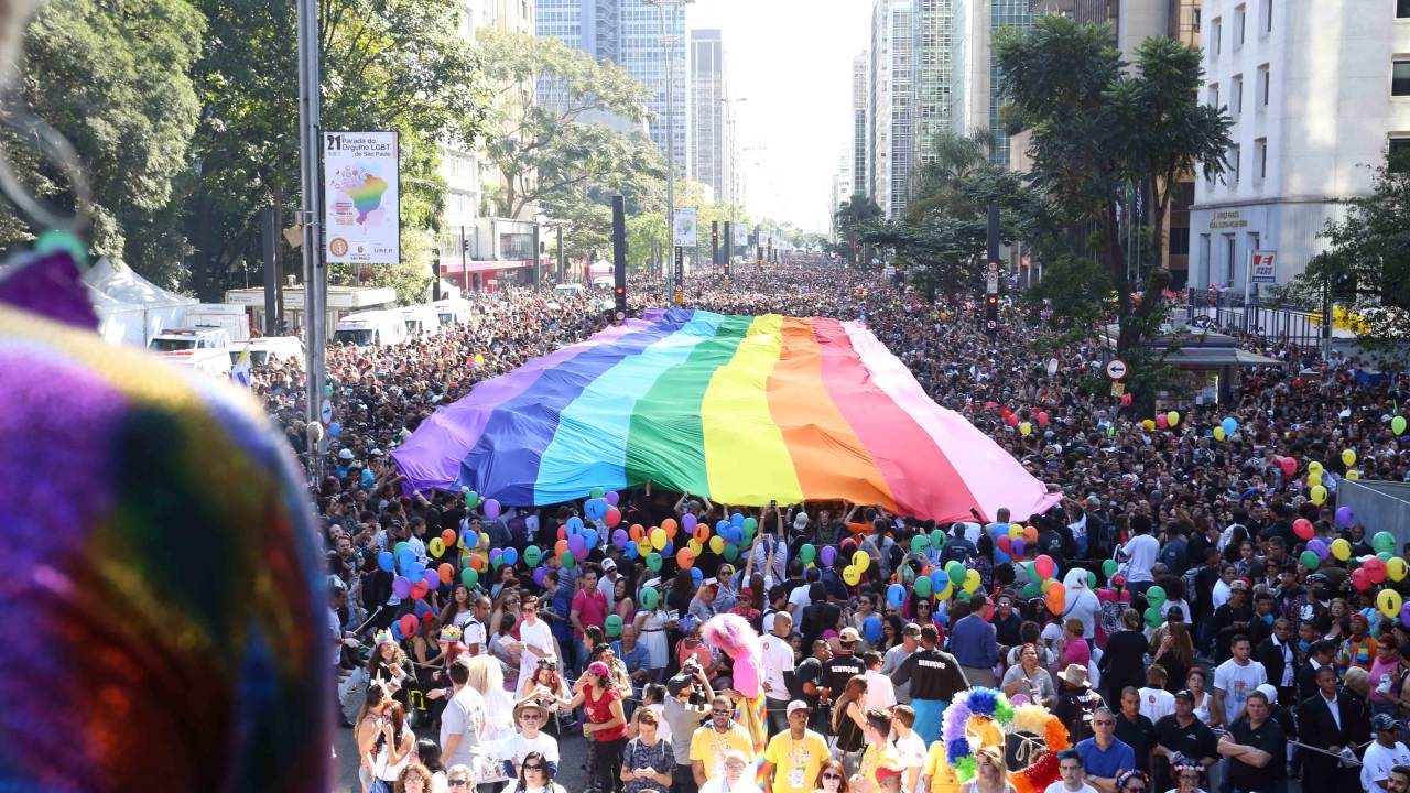Imagem mostra multidão reunida na Avenida Paulista, com bandeira LGBT estendida
