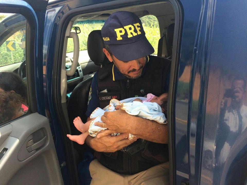 Policial segura o bebê enquanto aguarda socorro médico em acidente em Minas Gerais (Reprodução / Facebook)