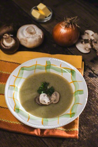 Mushroom soup and ingredients on vintage wooden table