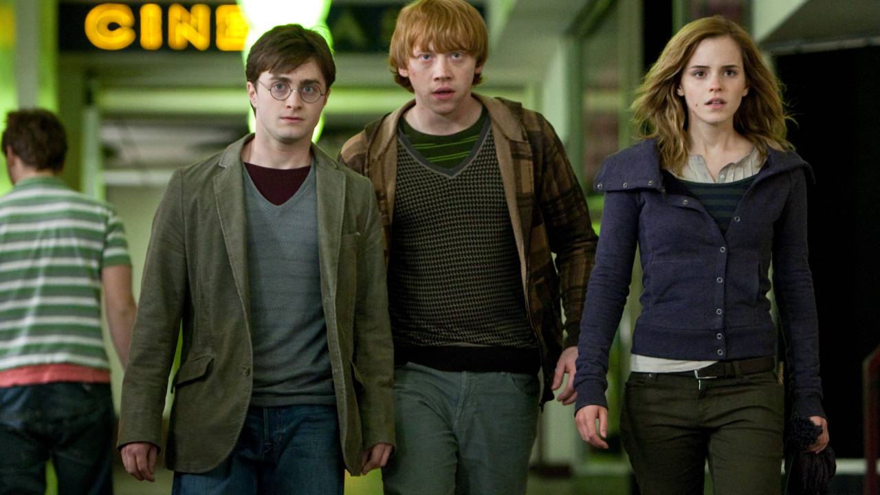 Harry (Daniel Radcliffe), Rony (Rupert Grint), Hermione (Emma Watson) aparecem andando lado a lado em saída de cinema