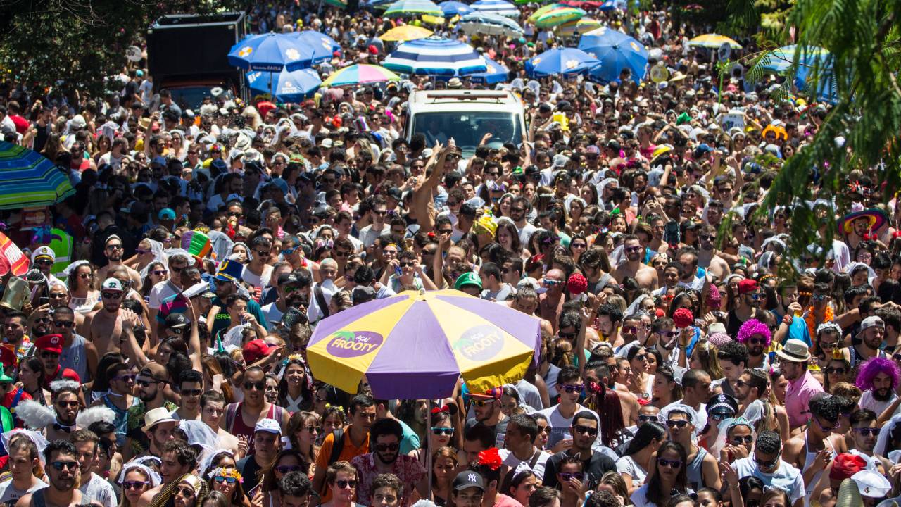 Imagem mostra Avenida Faria Lima lotada de foliões, com guarda-chuvas de vendedores ambulantes no meio da multidão