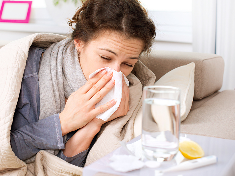A imagem mostra uma pessoa com gripe assoando o nariz