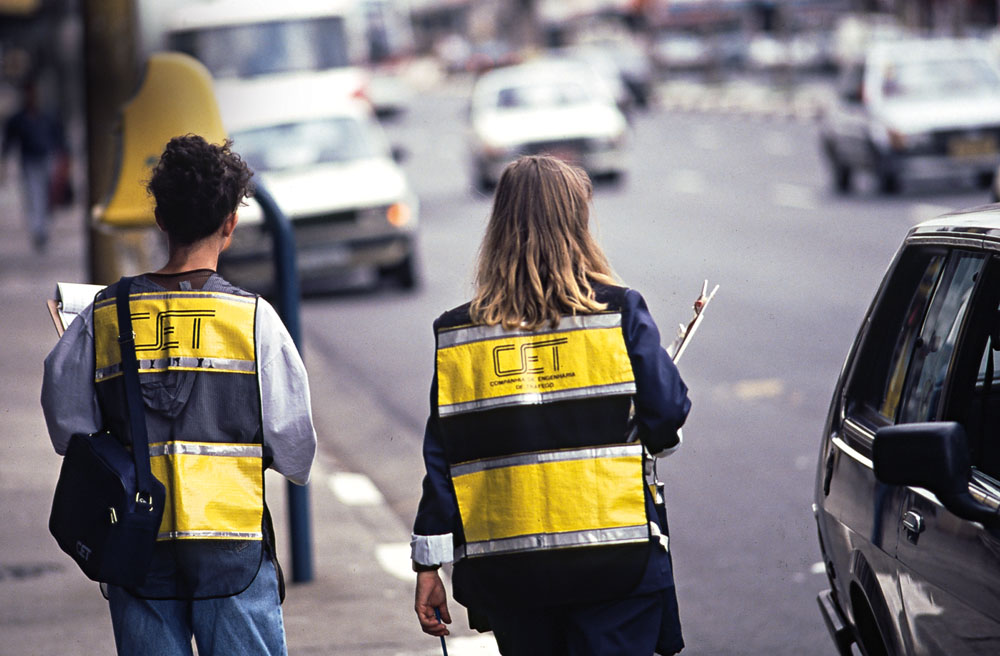 Imagem mostra dois fiscais da CET, com coletes com a inscrição da autarquia, de costas em rua de São Paulo