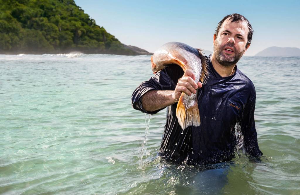 Homem no mar carrega peixe no ombro