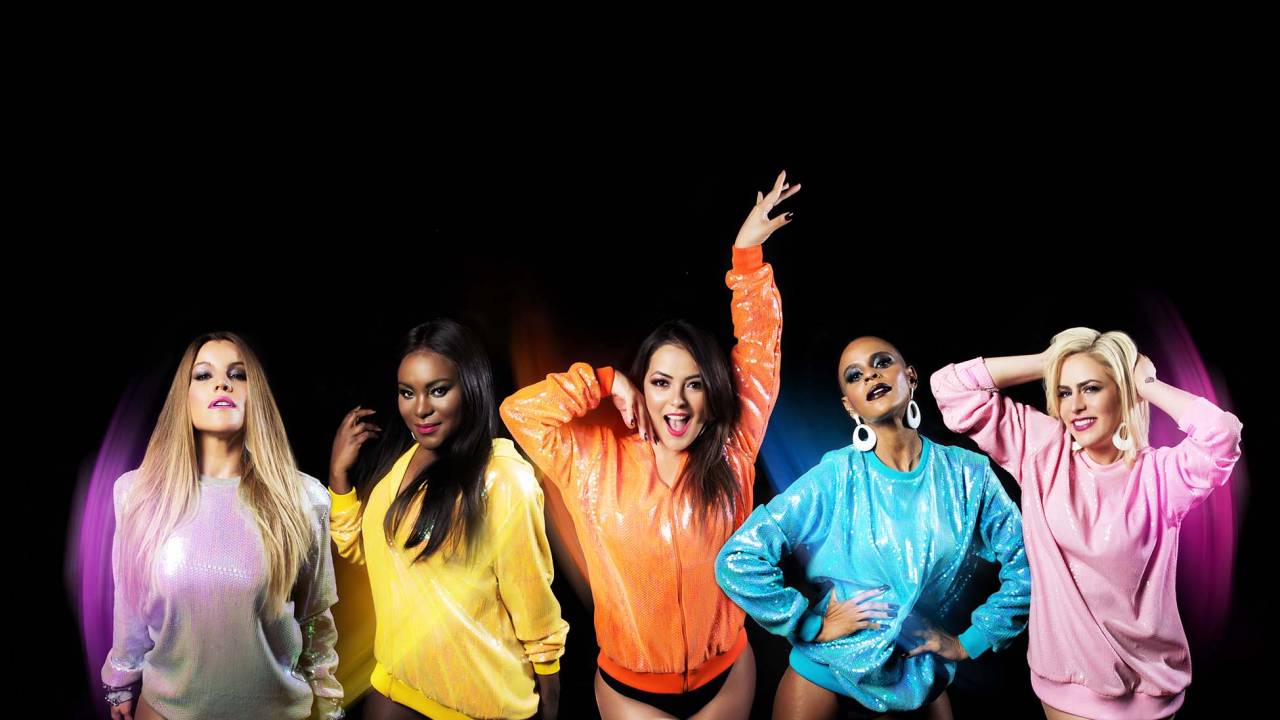Foto de fundo preto destaca as cinco cantoras da banda Rouge, lado a lado, cada uma com uma blusa de cor diferente. A partir da esquerda: lilás, amarelo, laranja, azul-claro e rosa.