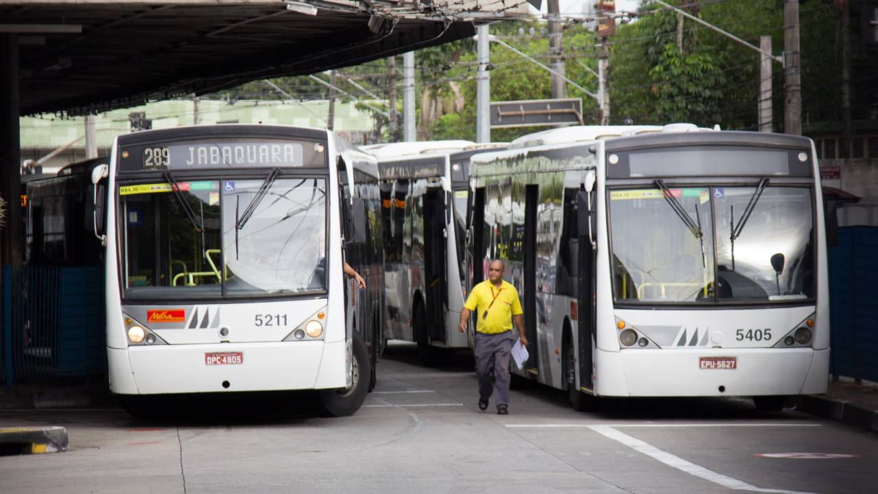 ônibus em terminal e homem entre os veículos