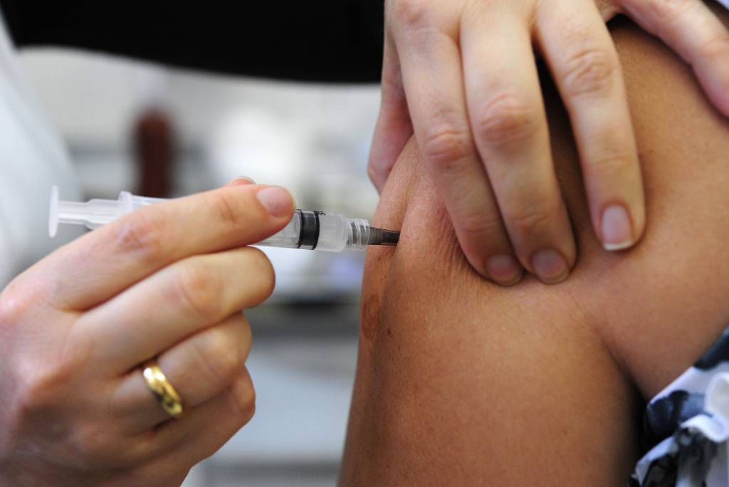 Imagem mostra enfermeira aplicando vacina no braço de paciente
