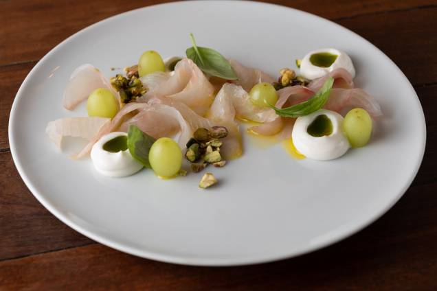 Amateigado de tão macio: crudo de robalo com azeite aromatizado por manjericão, uvas verdes, pistache e creme de ricota