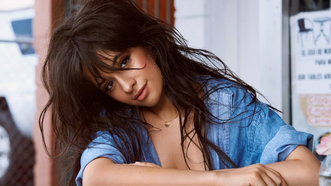 Camila Cabello posa de camisa jeans e cabelos bagunçados.