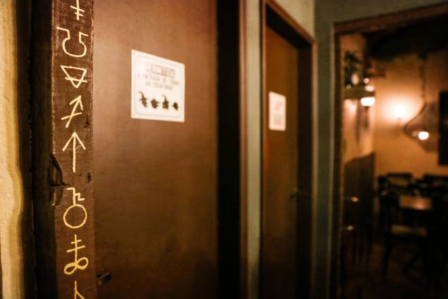 Detalhe na porta dos banheiros, símbolos místicos decoram o ambiente Detalhe na porta dos banheiros, símbolos místicos decoram o ambiente