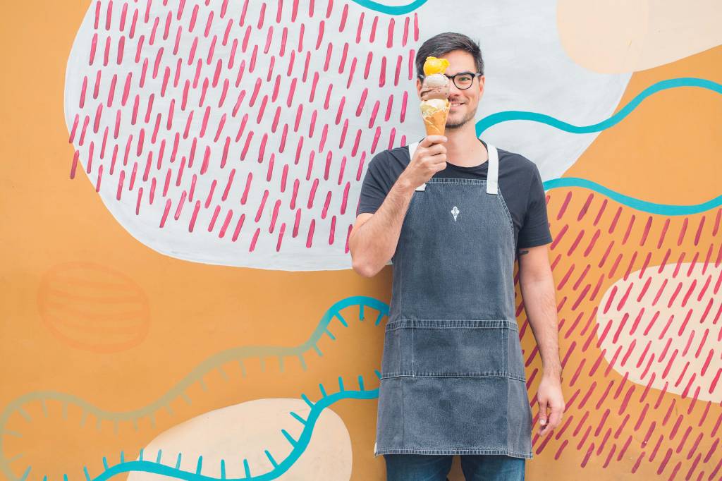 Thomas Zander posa em frente à parede colorida enquanto segura um sorvete