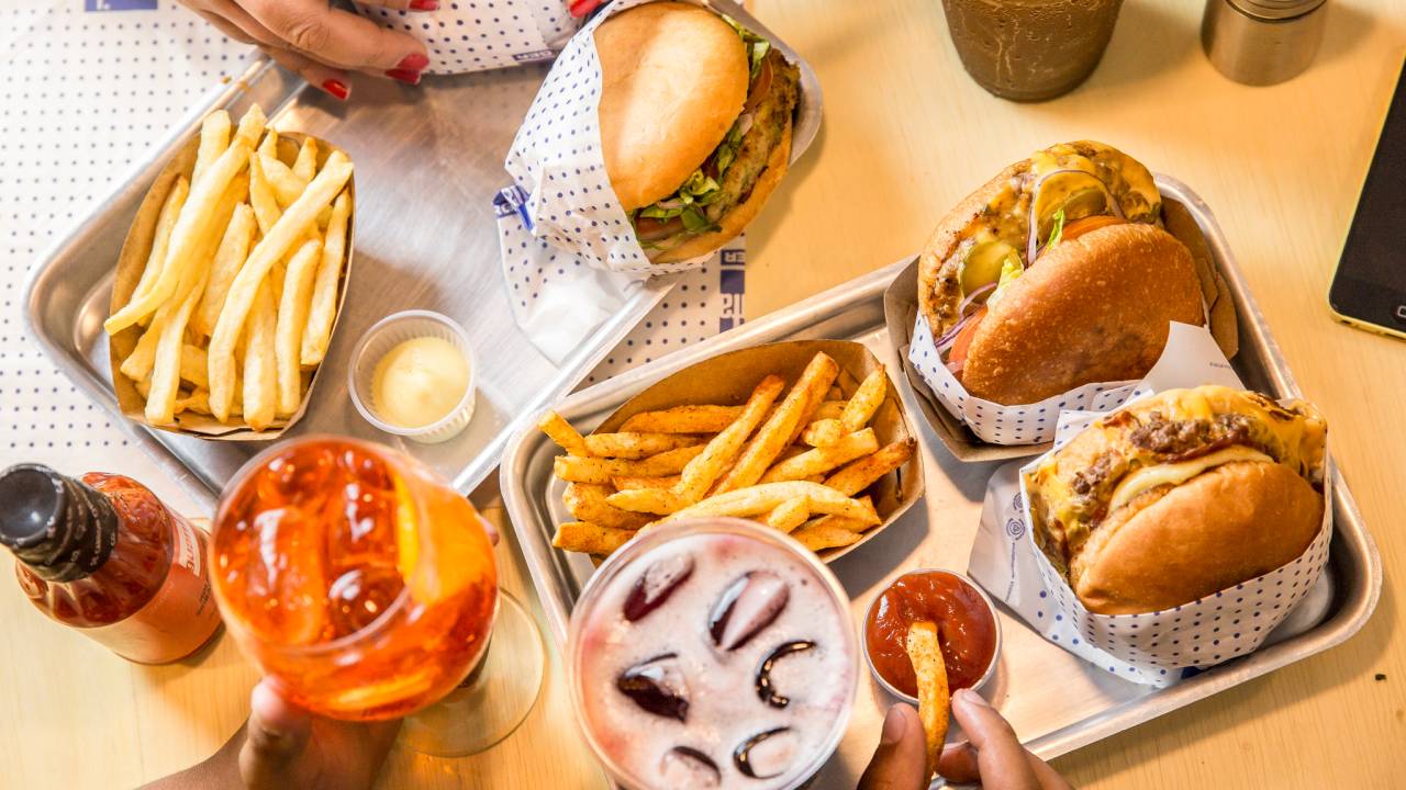 Mesa com hambúrgueres, fritas e bebidas