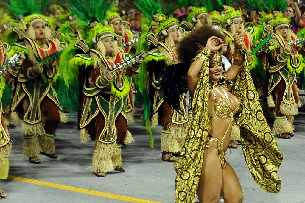 Imagem mostra bateria de escola de samba e mulher dançando no sambódromo do anhembi
