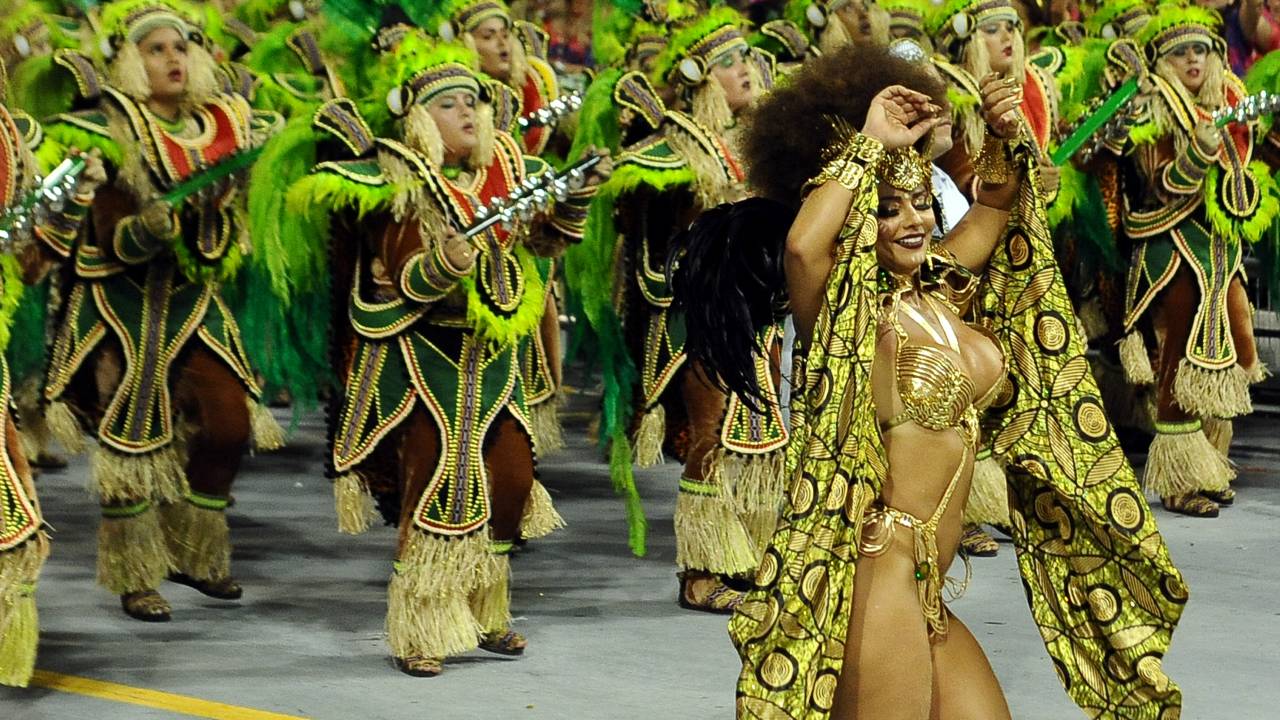 Imagem mostra bateria de escola de samba e mulher dançando no sambódromo do anhembi